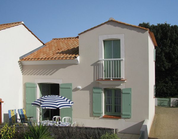 Façade de la maison avec son balcon et ses volets verts